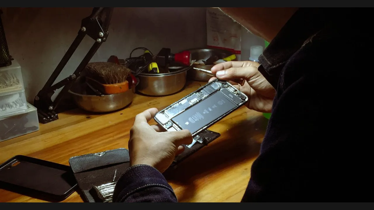 A technician repairing an opened smartphone on a workbench with tools